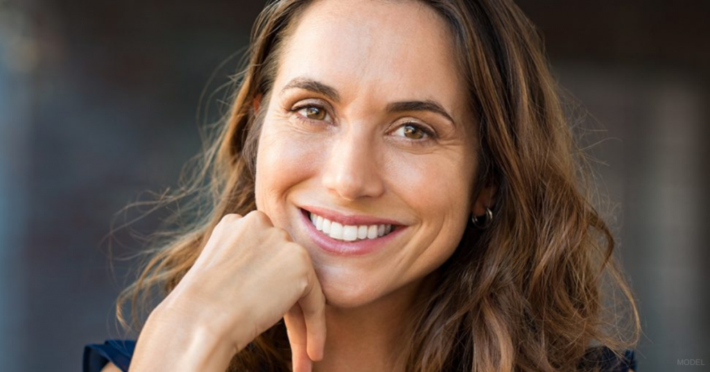 Woman resting her chin on her hand and smiling (model)