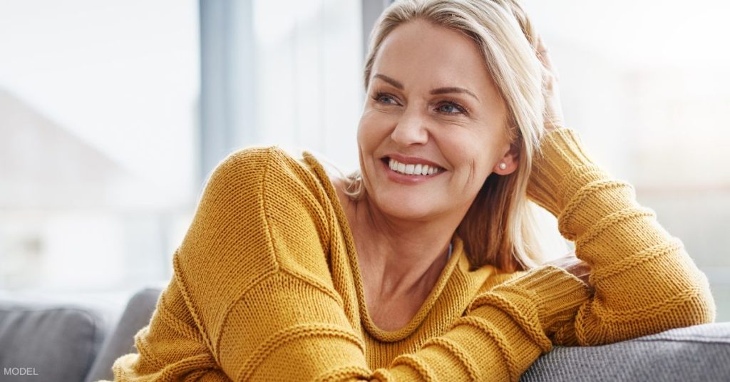 A mature woman wearing a sweater and smiling (model)