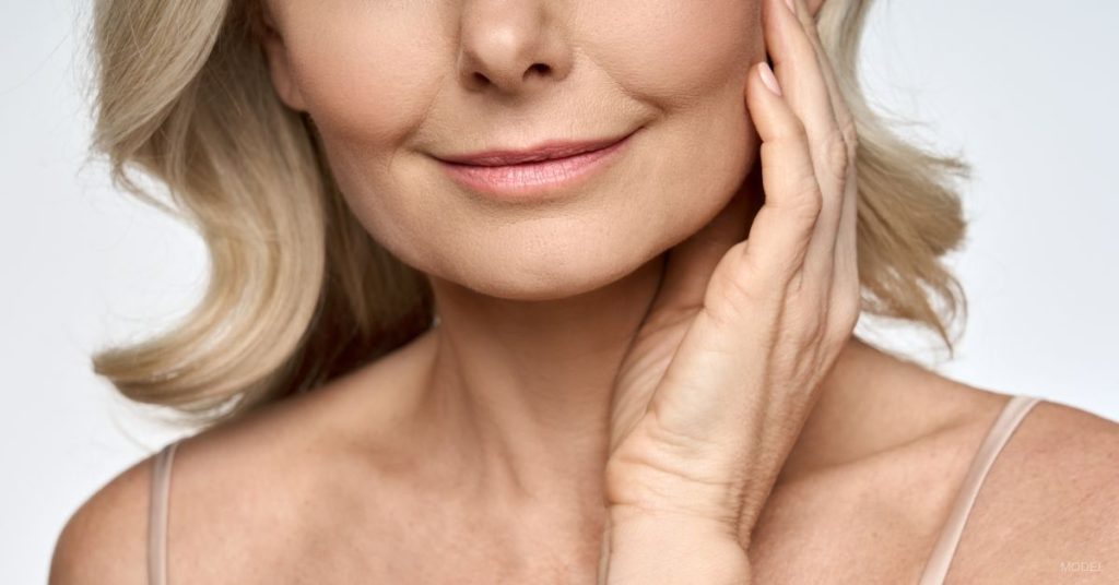 Mature woman with a smooth neck touching her cheek (model)