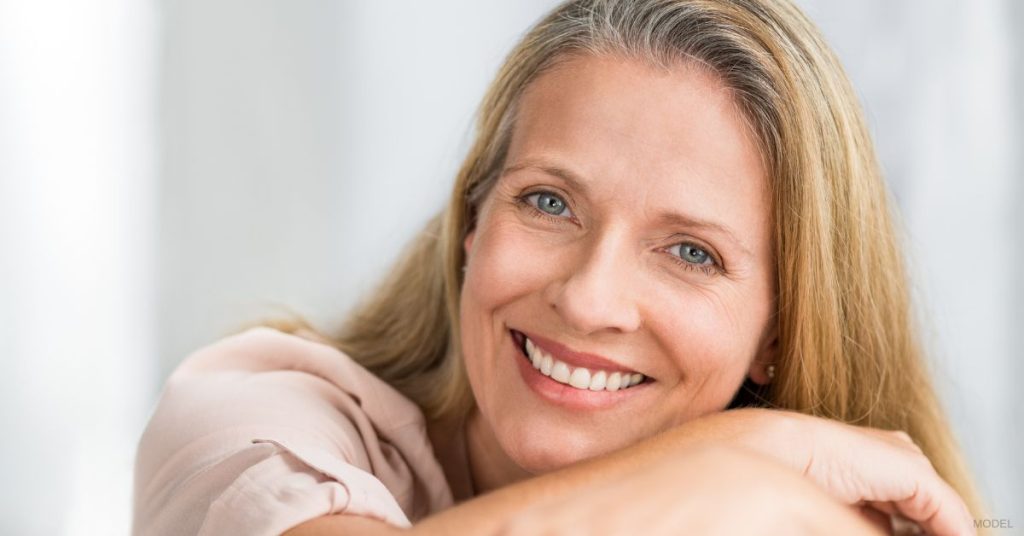 A woman smiling while sitting on a couch. (Model)